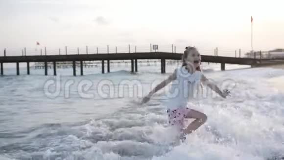 一个快乐的小女孩羡慕地兴奋地从岸边的巨浪中跳了出来孩子们快乐玩耍视频的预览图