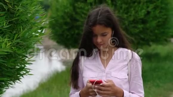 女士在湖边沿着公园小径散步在智能手机上聊天视频的预览图