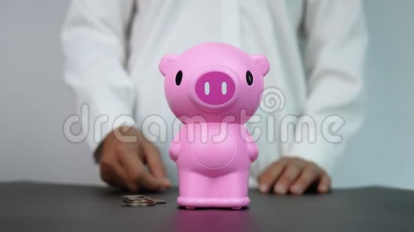 女人把硬币放进房间里的粉红色储蓄罐里省钱的概念视频的预览图