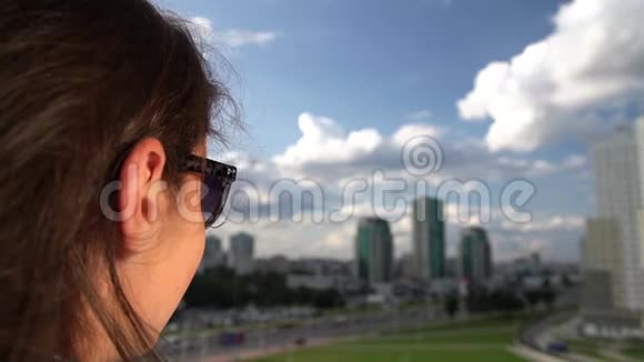 戴太阳镜的布鲁内特欣赏多云天空下的城市景色视频的预览图