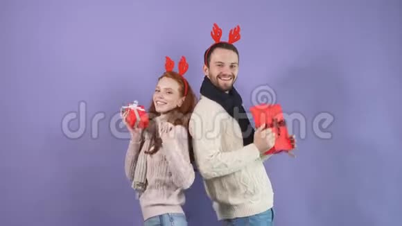 幸福的年轻夫妇穿着白色毛衣手里拿着圣诞礼物跳舞视频的预览图