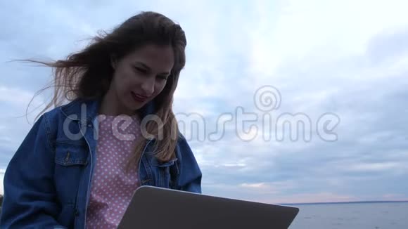 在户外工作的年轻女人围绕着她的大海天空海滩4K慢慢视频的预览图