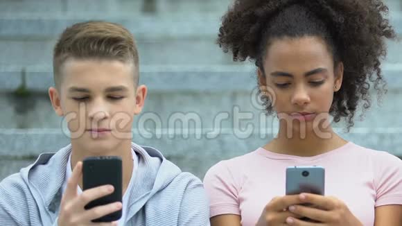 混血女性和不高兴的白种人男性青少年在手机上玩游戏视频的预览图