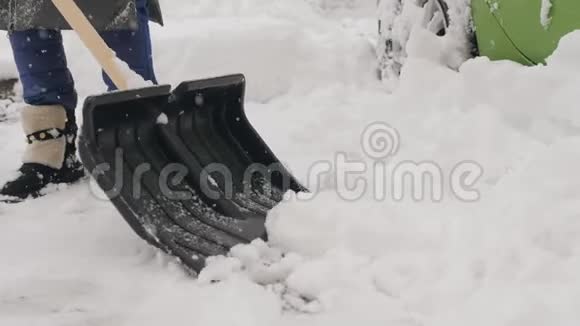 一个拿着铲子的人在他的车周围擦干净的雪在雪地里视频的预览图