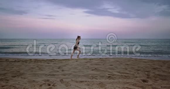 在一个大海滩边运动的女士早上开始在海边跑步非常集中令人惊叹的天空景色视频的预览图