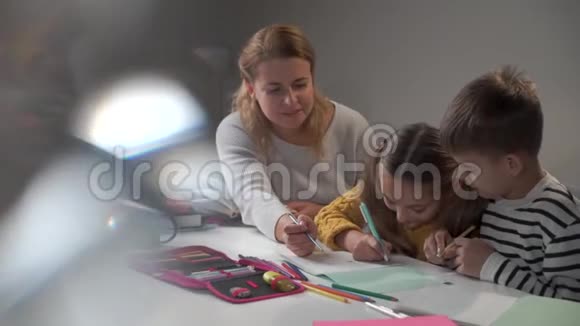 积极的高加索家庭坐在桌子旁做作业可爱的孩子们带着他们微笑的孩子做任务视频的预览图