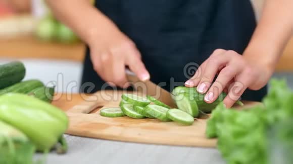 女性家庭主妇用刀切新鲜黄瓜享受健康的生活方式视频的预览图