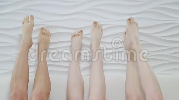 女孩们躺在沙发上双脚上山女孩们在白色背景上移动脚视频的预览图