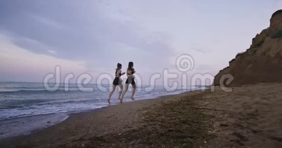 海滩上美丽的风景两位迷人的女士穿着运动服一起晨跑视频的预览图