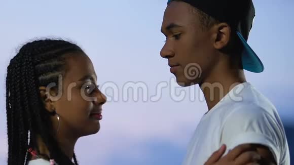 漂亮的非裔美国青少年夫妇温柔地拥抱天空背景支持视频的预览图