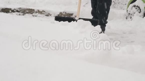 一个拿着铲子的人在一夜暴风雪后清除了汽车周围的积雪视频的预览图