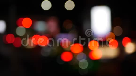 在黑暗模糊的背景下美丽的闪闪发光的夜晚车灯在交通中闪耀着圆圆的五颜六色的光视频的预览图