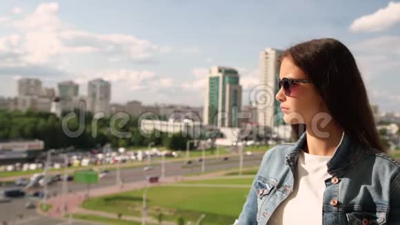 戴墨镜的布鲁内特修复头发欣赏城市风景视频的预览图