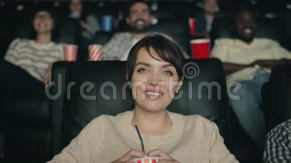 欢快的女人笑着在电影院看电影捧着饮料视频的预览图
