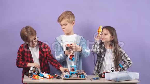 白人儿童试图连接电线和组装机器人隔离在紫色背景视频的预览图