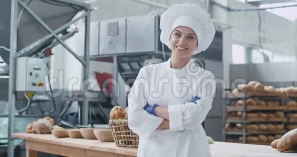 可爱的面包师女人在镜头前直视和微笑的大型商业厨房工业机器上视频的预览图