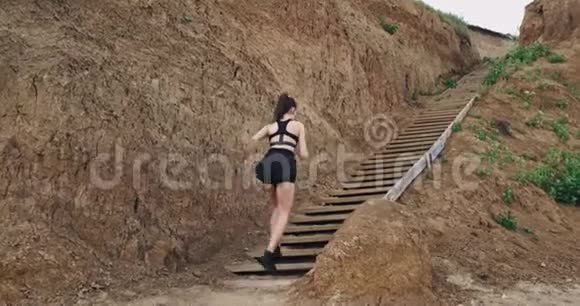 一个穿着黑色运动装备跑上台阶的年轻女子的远射视频的预览图