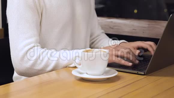 有笔记本电脑和咖啡杯的年轻人在咖啡店视频的预览图