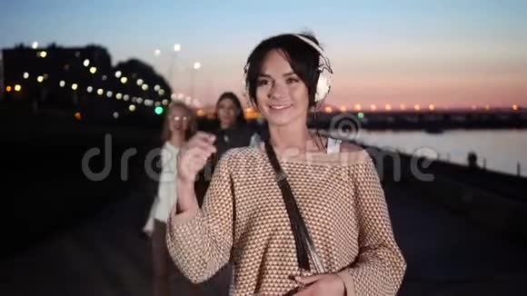 年轻漂亮可爱的时髦女人在耳机里散步和听音乐视频的预览图
