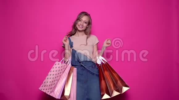 穿着牛仔服装拿着信用卡和购物袋的年轻女子微笑视频的预览图