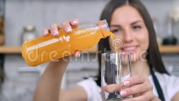 贴心的微笑女孩将清爽的维生素橙汁倒入玻璃中享受健康的生活方式视频的预览图
