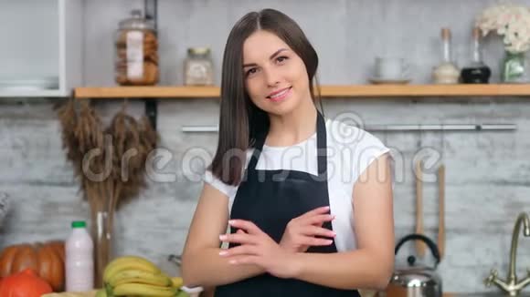 穿着围裙的美女在厨房内部摆着交叉的手视频的预览图