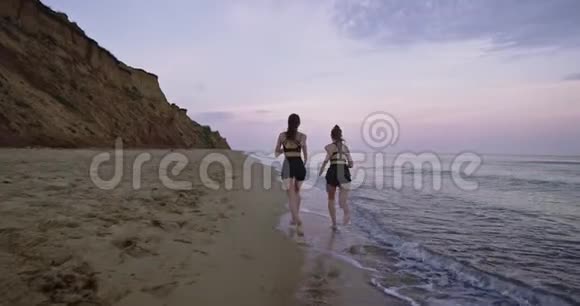 令人惊叹的景观视频两位年轻女士早上在海滩上通过海水奔跑视频的预览图