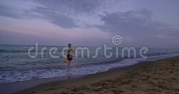集中女士在海滩边的中间练习瑜伽站起来欣赏冥想姿势视频的预览图