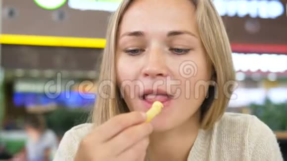 女人吃薯条坐在商场咖啡馆里微笑视频的预览图