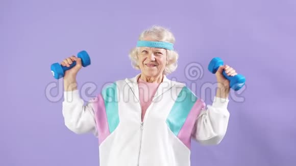 快乐的老年妇女用一双哑铃和微笑锻炼视频的预览图