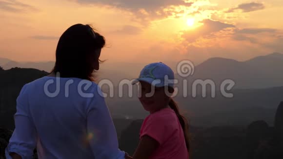 一个女人和一个十几岁的女孩在山上日落的背景下游客欣赏日落视频的预览图
