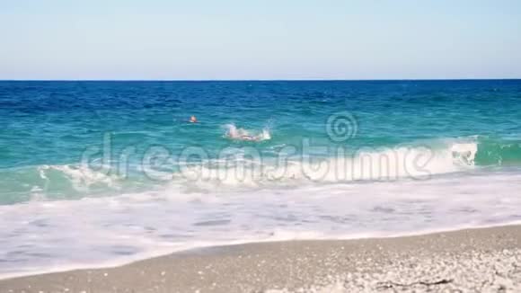 碧蓝的海水中两个人在游泳夏天炎热的晴天柔软的海浪在海上在海滩上波浪波浪波浪波浪浪视频的预览图