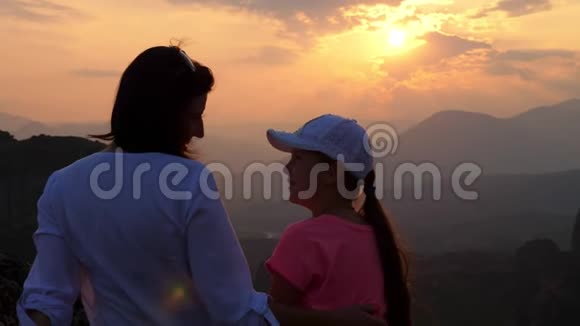 一个女人和一个十几岁的女孩在山上日落的背景下游客欣赏日落视频的预览图