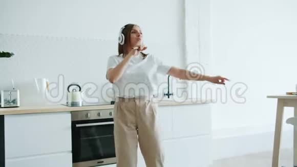 欢乐的女士在家里用勺子唱歌用耳机听音乐视频的预览图