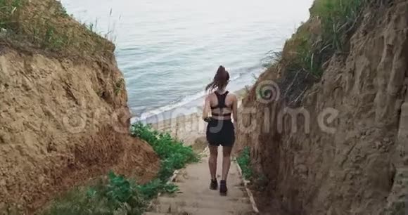 一个年轻瘦小的运动女孩穿着运动服轻微地走下楼梯在风景优美的自然中视频的预览图
