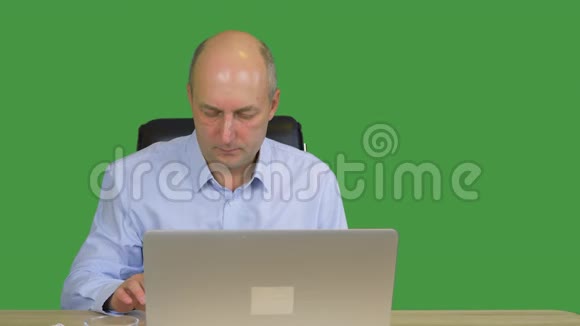 在办公室工作的商人在绿色背景下使用笔记本电脑专注的商人显示食指冷漠和视频的预览图