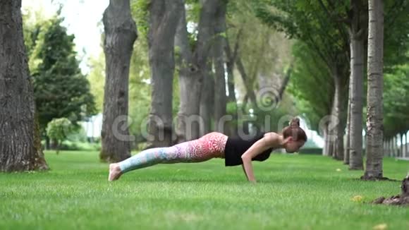 美丽的女孩在公园里慢动作地做瑜伽体式视频的预览图