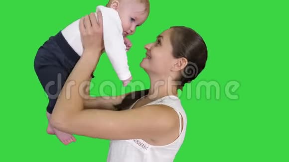 积极的小可爱男孩和美丽的妈妈把她的孩子上升到绿色屏幕Chroma键视频的预览图