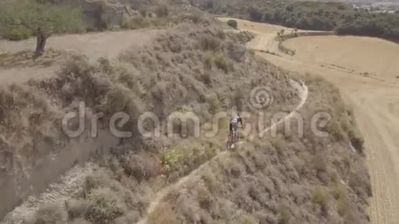 一名运动男性骑着山地自行车在乡村的空中俯瞰视频的预览图