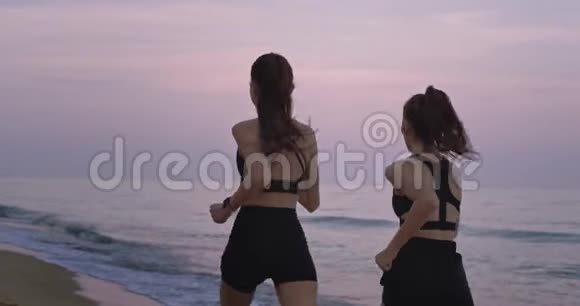 适合身材的女士一起穿过海滩在早晨享受健康的生活方式视频的预览图