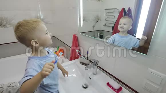 一个穿睡衣的小男孩在浴室前刷牙视频的预览图