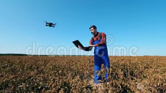 一片枯死的田野和一个操作无人机的农业科学家视频的预览图