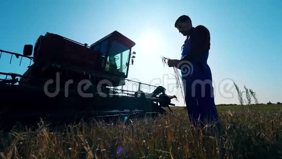 男性耕耘者农民站在收割机旁边的田里视频的预览图