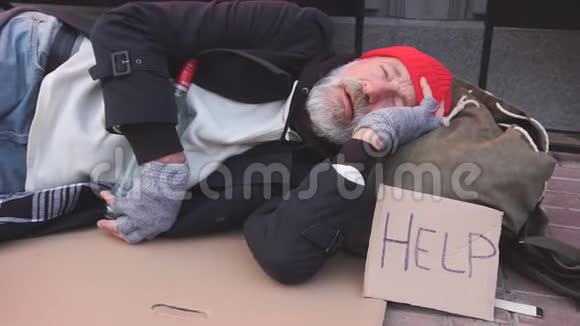 绝望的乞丐穿着旧衣服躺在纸板箱上要钱寻求任何帮助视频的预览图