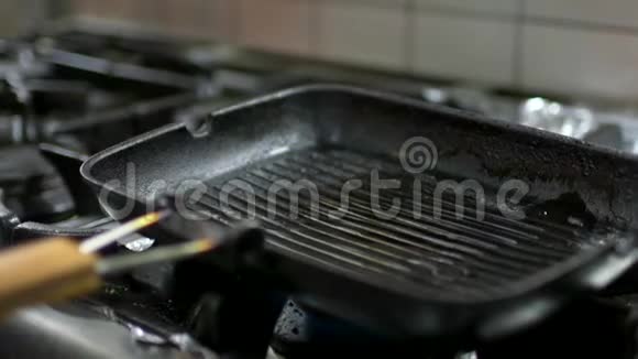 专业厨师在煎锅中倒入食用油同时站在炉子旁边视频的预览图