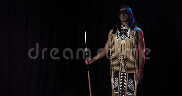 一个肌肉发达的美国土著人手持长矛站在红光和蓝光中4K视频的预览图