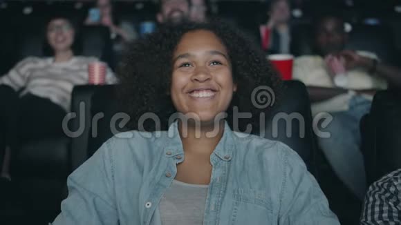 在电影院里欣赏电影的快乐非裔美国女人笑得慢视频的预览图
