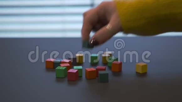 年轻的女性手红色指甲在毛衣混合彩色木块并把其中一些放在中间视频的预览图