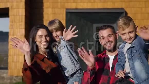 现代家庭幸福快乐的漂亮肖像在美丽的房子附近的镜头上摆姿势挥舞双手视频的预览图