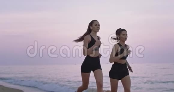 美丽的两位女士在海滩边跑步集中享受早晨练习运动的时刻慢慢慢慢视频的预览图